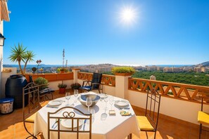 A terrace with a table set for dining, outdoor seating, and a view of the cityscape.