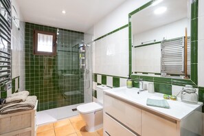 A bathroom with a shower, toilet, sink, and a mirror.