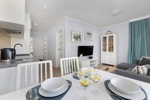 Una sala de estar moderna con comedor, cocina y televisor.