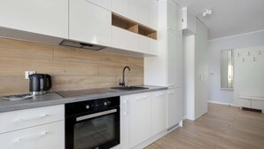 A modern kitchen with white cabinets, a built-in oven, a coffee maker, and a sink.