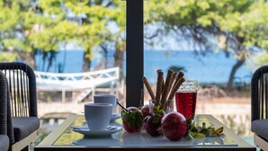 A table with a drink, fruits, and a cup, overlooking a bridge and trees. - Villa with Sea View, Shared Garden & Wi-Fi (Lefkada)