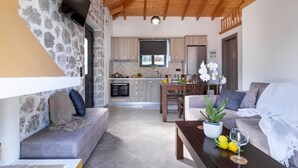 Een modern interieur met een stenen muur, houten plafond, een keuken met kasten, een eethoek en een woonkamer met een bank en een tafel met citroenen en een glas.
