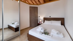 Een slaapkamer met een houten plafond, een grote spiegel, een bed met witte lakens en een nachtkastje met een lamp.