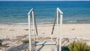 Een strand met een metalen ladder naar het water.