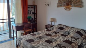 A bedroom with a bed, a desk, a chair, a bookshelf, and a decorative fan. - Magnificent sea view 150 m from the beach, private domain of Gaou Benat (Bormes-les-Mimosas)