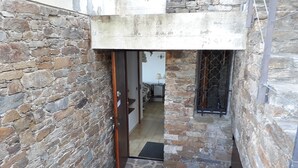 A narrow stone-walled corridor with a metal gate, a door, and a small table with a chair. - Magnificent sea view 150 m from the beach, private domain of Gaou Benat (Bormes-les-Mimosas)