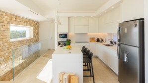 Eine moderne Küche mit einer Steinwand, einer zentralen Kochinsel und einem Edelstahl-Kühlschrank.