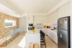 Eine moderne Küche mit einer Steinwand, einer zentralen Kochinsel und einem Edelstahl-Kühlschrank.