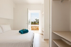 A hotel room with a bed, a blue towel, a white pillow, a wardrobe, and a view of the outdoors.