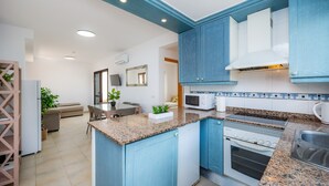 A modern kitchen with blue cabinets, a granite countertop, a built-in oven, and a microwave.