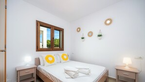 A bedroom with a bed, two bedside tables, a window, and wall decorations.