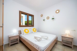 A bedroom with a bed, two bedside tables, a window, and wall decorations.