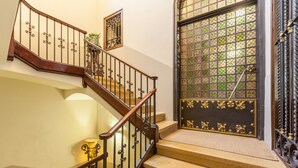 A staircase with a wooden handrail and metal balusters, leading to a door with a decorative glass panel.