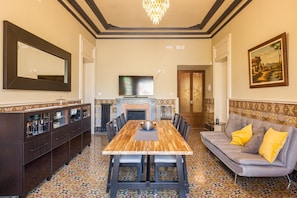 A dining area with a wooden table, chairs, a sofa, a fireplace, and a television. - Holiday Home 'Apartament Xarello' with Terraces (Vilafranca del Penedes)