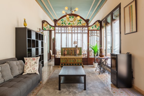 A living room with a sofa, a coffee table, a bookshelf, a decorative cabinet, and a television.