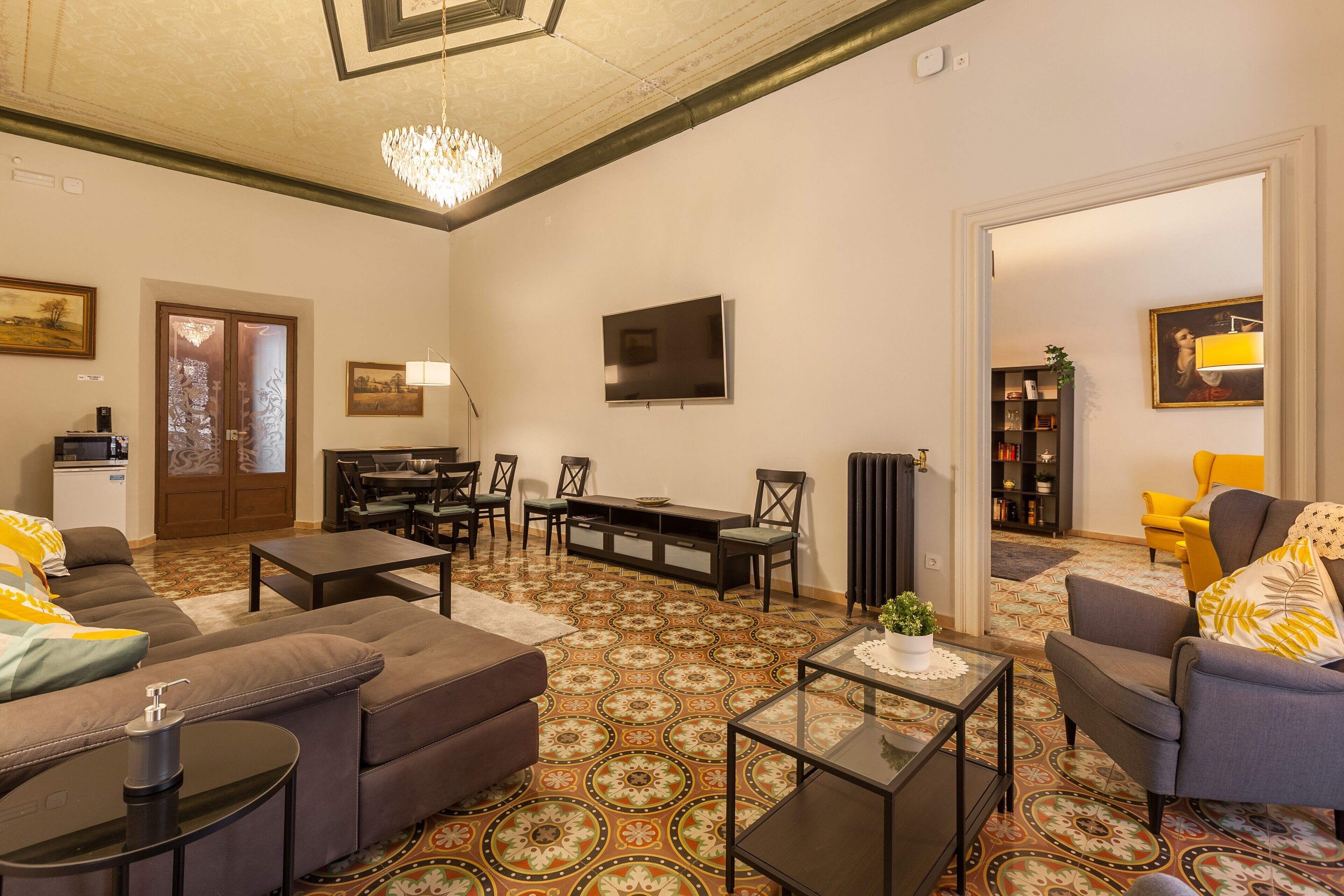 A living room with a sofa, coffee table, TV, and patterned flooring.