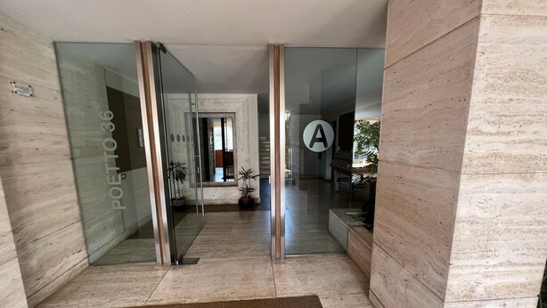 Un intérieur moderne avec des portes en verre, un sol en marbre et une lettre « A » bien visible sur le mur.