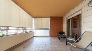 Un balcon avec un sol carrelé, une chaise, une table et un canapé.