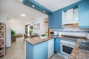 A modern kitchen with blue cabinets, a granite countertop, a built-in oven, and a microwave.