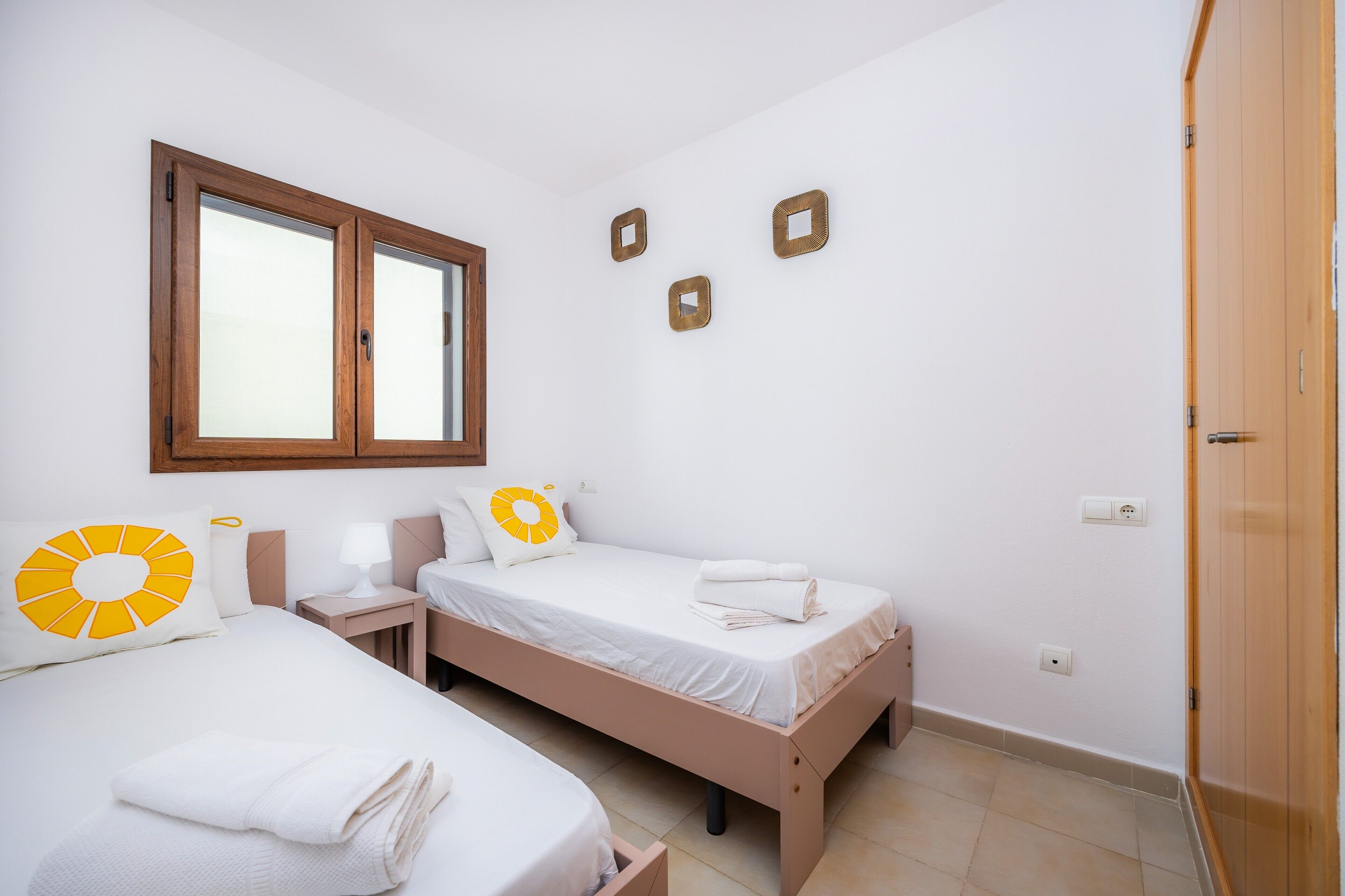A bedroom with two beds, a window, and a wooden wardrobe.