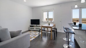 Cocina moderna con comedor, televisor y vistas al exterior.