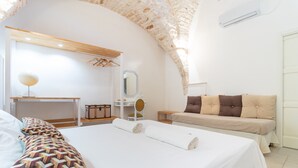 Une chambre à coucher avec un grand lit, un bureau, une chaise, un canapé et un miroir.