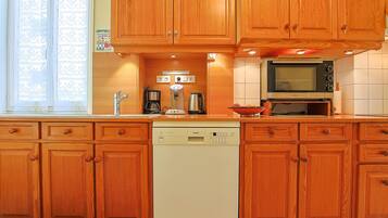 A kitchen with wooden cabinets, a Bosch dishwasher, a microwave, and a coffee maker.