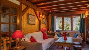 L’intérieur d’un chalet en bois, avec un canapé, une table et une fenêtre donnant sur les arbres.