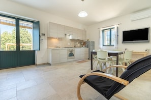 A modern kitchen with a dining area, a TV, and a view of the outdoors.