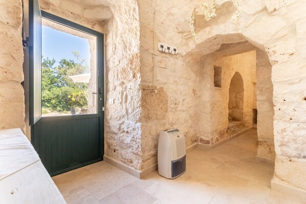 A room with a stone wall, a door with a window, a heater, and a tiled floor.