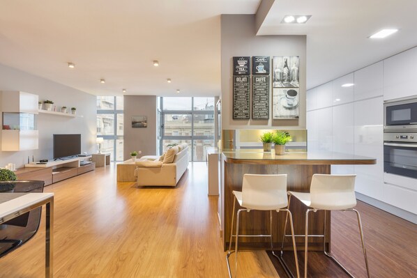 Une cuisine moderne avec un coin bar, un plancher en bois et une grande fenêtre.