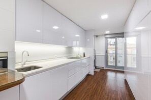 A modern kitchen with white cabinetry, a stainless steel sink, and a wooden countertop.