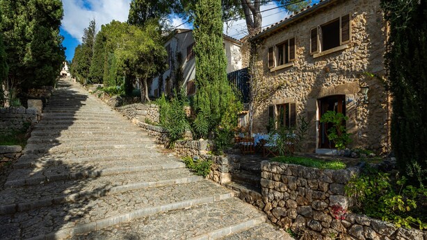A stone staircase leading to a rustic building with a stone wall and greenery. - Vacation Home "Casa en Centro Histórico Pollença" with Private Terrace, Garden & Wi-Fi (pollensa)