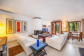 A living room with white sofas, a coffee table, a TV, and artwork on the wall.