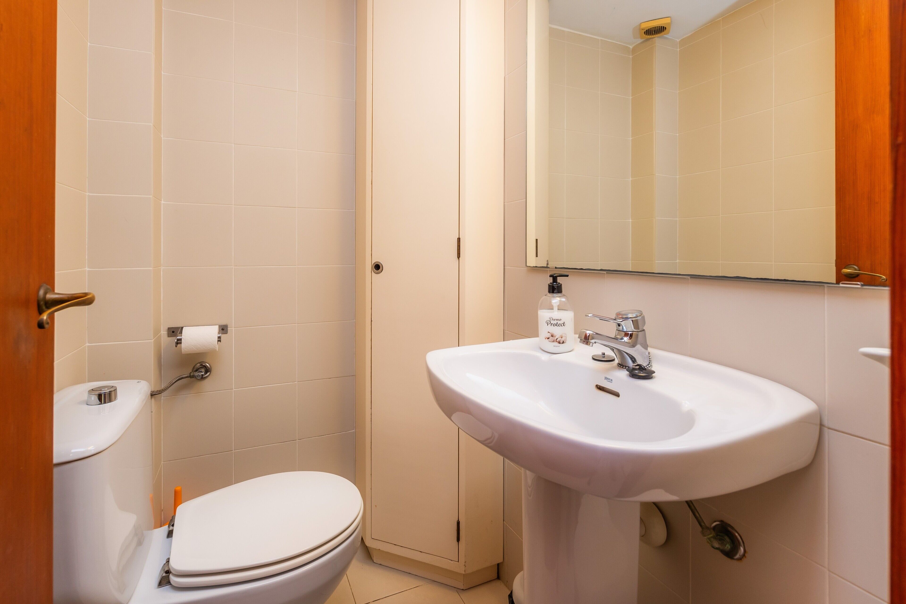 Une salle de bain équipée de toilettes, d’un lavabo, d’un miroir et de papier toilette.