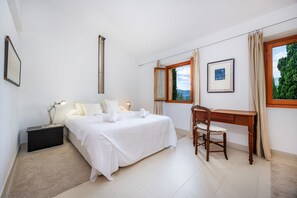 Un dormitorio con cama, mesita de noche, escritorio, silla y ventana con vistas.