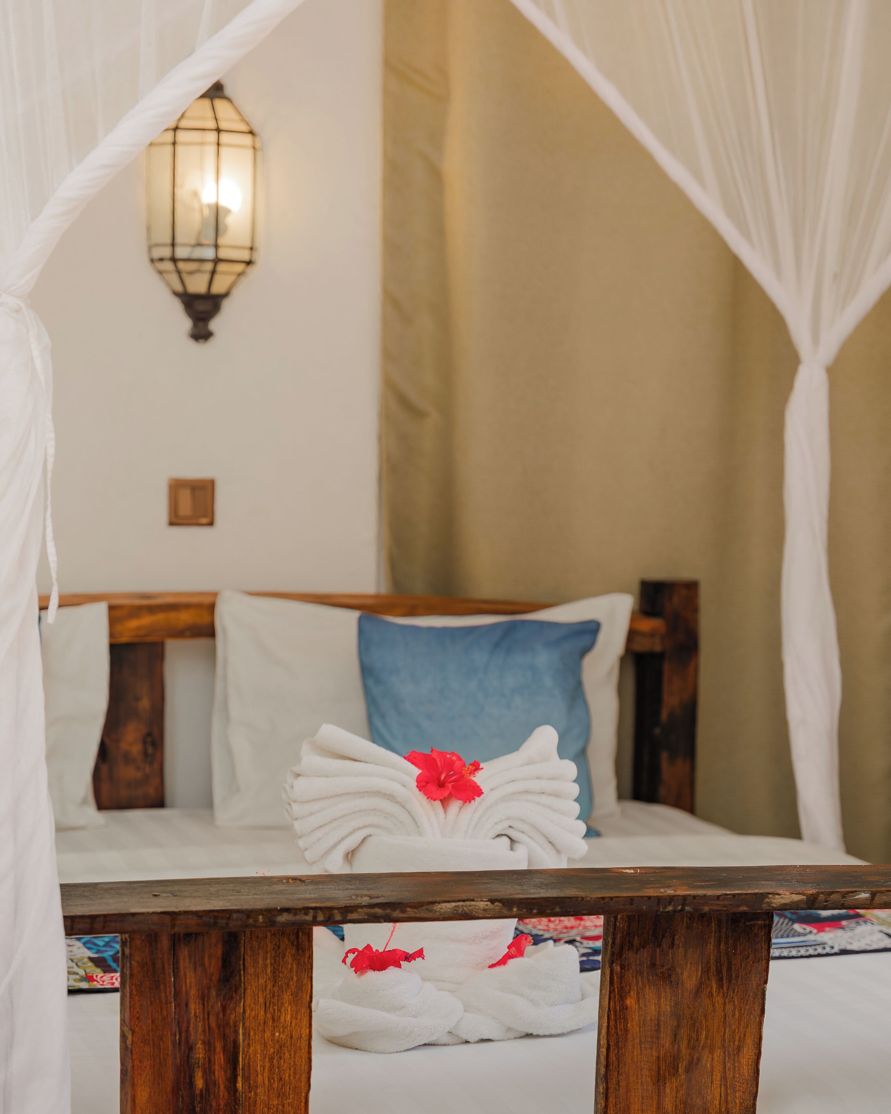 A bed with a canopy, a bedside lamp, and a floral arrangement on the bed.