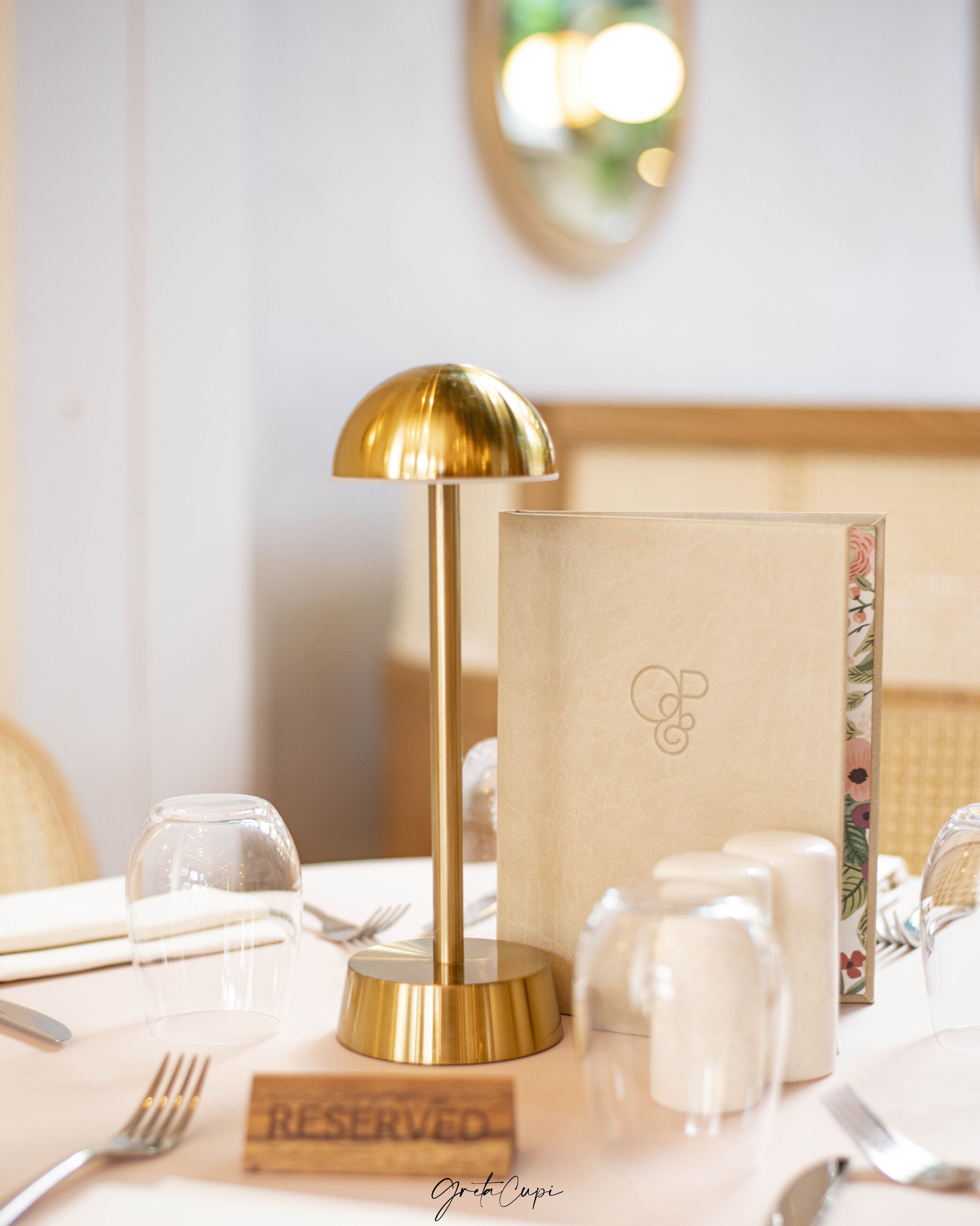 A table set with a gold lamp, a menu, and a 'RESERVED' sign.