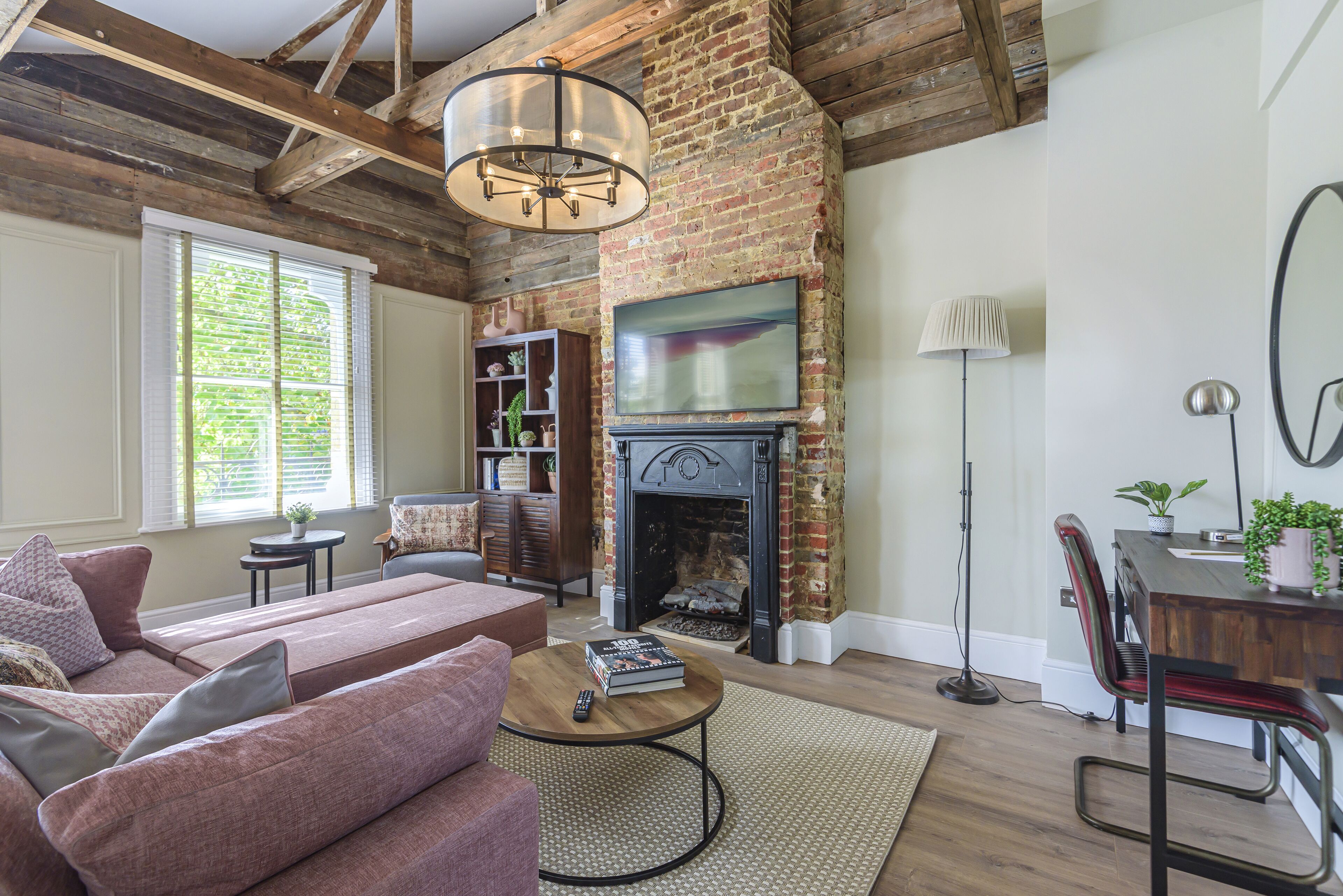 A living room with a brick fireplace, a television, a sofa, and a coffee table.