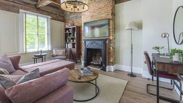 A living room with a brick fireplace, a television, a sofa, and a coffee table.