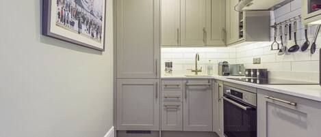 A kitchen with light grey cabinets, a stainless steel oven, and a tiled backsplash.