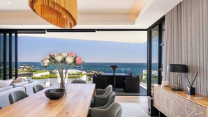 Uma área de refeições moderna com mesa de madeira, cadeiras cinzas e um vaso de flores.