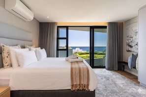 Ett hotellrum med en stor säng, havsutsikt och modern design.
