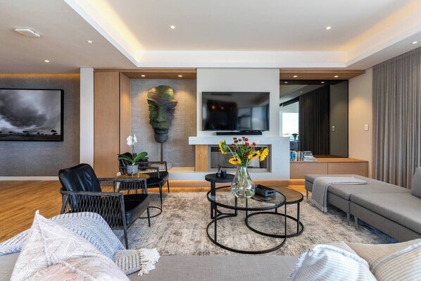 A modern living room with a sofa, coffee table, and a flat-screen TV mounted on the wall.