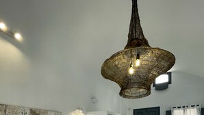 Een moderne hotelkamer met een witte bank, een gestreept voetenbankje, een groot decoratief wandkunstwerk, een bijzondere hanglamp en een bed met een witte hoofdeinde.