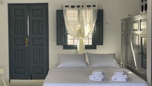 Een hotelkamer met een bed, een kledingkast, een raam met gordijnen en een deur.