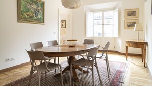 A dining area with a round wooden table, six chairs, a decorative bowl, and a hanging light fixture.