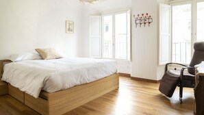 A bedroom with a wooden bed, a chair, and a large window.