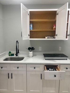 A kitchen with a double sink, a stove, and open cabinets.