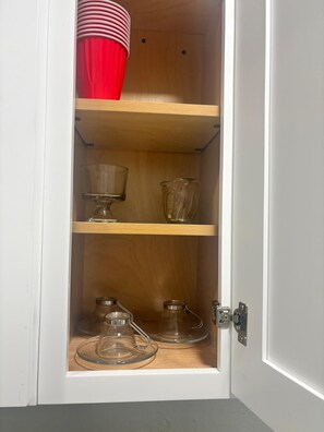 A white cabinet with three shelves, each holding different glassware. - #11 The Paradise in-law Suite by Joyful Moments (Tampa)